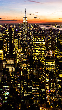 Foto panorâmica de cidade ao anoitecer com muitos prédios iluminados