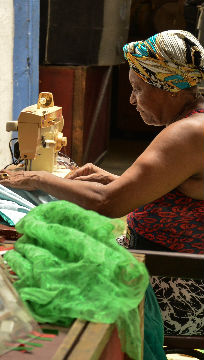 moça sentada costurando roupa na região portuária 