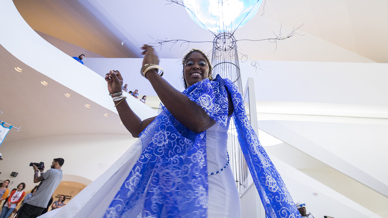 Mulher negra com trajes tradicionais da cultura negra dançando