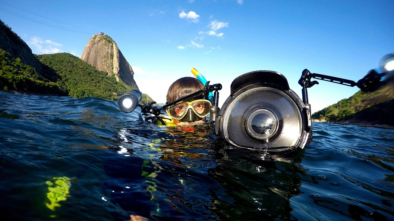 Na foto, o cineasta Ricardo Gomes mergulhando na Baía de Guanabara com roupas e acessórios de mergulho e câmera especial para água.